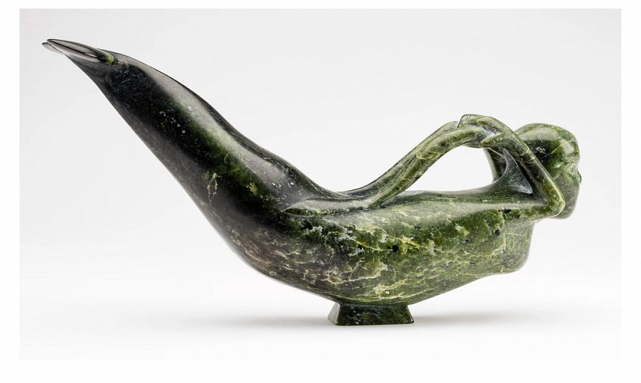 Osuituk Ipeelee, Sedna, 1983
5 3/4 x 11 3/4 x 3 in.
Osuitok Ipeelee was the finest and most versatile of the first generation Cape Dorset carvers.  It is well known that Osuitok was a great admirer of the female form; among his favourite subjects were young women engaged in a variety of pursuits: fishing, performing chores, and even playing a concertina. In comparison his depictions of the Inuit sea goddess are relatively few, which is surprising given that many other Inuit artists have carved Sedna as a creature with beautiful female attributes. There is however one depiction by Osuitok that is quite similar, a contemporaneous version in light green stone that graced the cover of Alma Houstonâ€™s book Inuit Art: An Anthology [1]. Although some of the details differ, the two sculptures are similar in size, pose, and overall look.

Osuitokâ€™s Sea Goddess has the look of a European-style mermaid with a human head, arms and breasts, and a beluga-like lower body. Beautifully balanced on a small base, her gracefully arched body performs a seal-like balletic swoop, while her hands grasp long braids that seem to transform into fronds of seaweed.


1. Alma Houstonâ€™s anthology also contains the article â€œOsuitok Ipeeleeâ€ by Jean Blodgett which illustrates the sculpture on page 53.


References: For a similarly posed and styled depiction of the sea goddess by Osuitok from 1983, see Jean Blodgett, â€œOsuitok Ipeeleeâ€ in Alma Houston, ed., Inuit Art: An Anthology, (Winnipeg, Watson & Dwyer, 1987), p. 53 and front cover.
03548-1